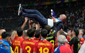 Spain players throw coach Luis de la Fuente in the air after winning the final match against England. [Matthias Schrader/AP Photo]